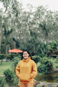 Portrait of young woman standing against trees