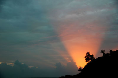 Low angle view of silhouette trees against dramatic sky