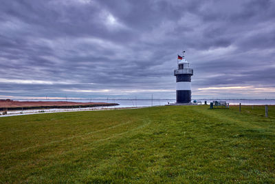 Lighthouse on beach by sea against sky