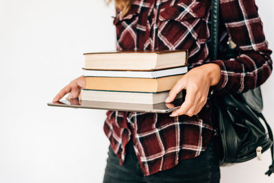 Midsection of woman holding books against white background