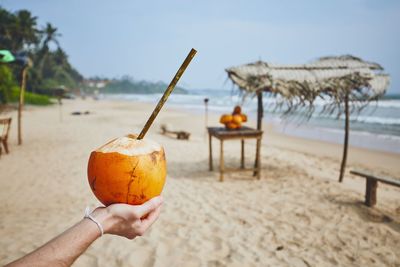 Hand holding ice cream cone on beach