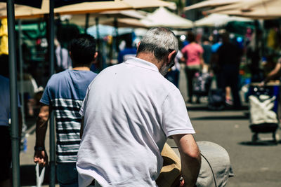 Rear view of man standing on street in city