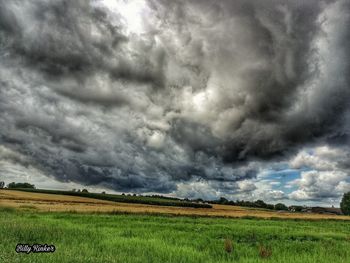 Scenic view of field against storm clouds