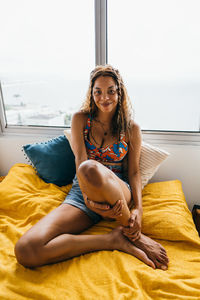 Young woman sitting on bed at home