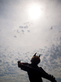 Silhouette boy against cloudy sky