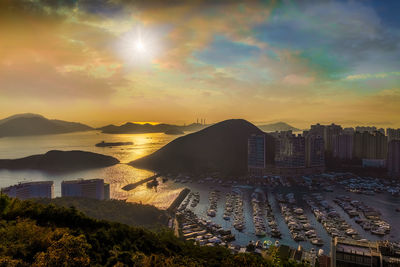 High angle view of sea and buildings against sky during sunset