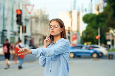 Young businesswoman talking on mobile phone while standing in city