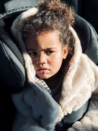 Portrait of cute girl with curly hair in carseat 