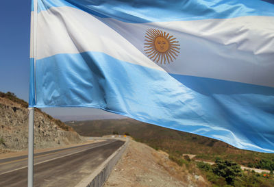 Close-up of flag on landscape against blue sky