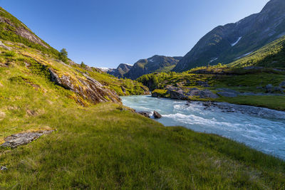 Scenic view of river amidst mountains against clear sky