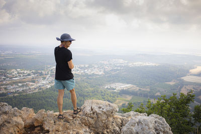 Man from behind standing on the edge of the mountain and watching a landscape. hiking concept. 