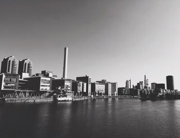 Buildings by river against clear sky