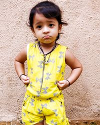 Portrait of cute boy standing against yellow wall