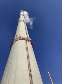 Low angle view of smoke coming out of huge power plant chimney stacked against sky