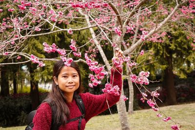 Portrait of beautiful woman standing against pink flowers