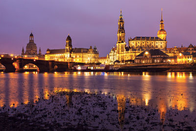 Illuminated buildings in city at sunset