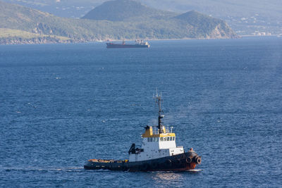 Ship sailing on sea against mountain