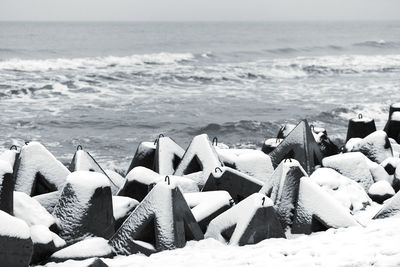 Concrete breakwaters covered with snow against background of winter sea. coastal protection in snow