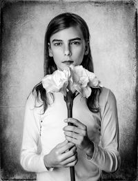 Portrait of young woman sitting against wall