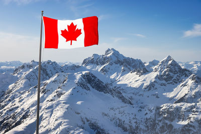 Red flag on snowcapped mountain against sky