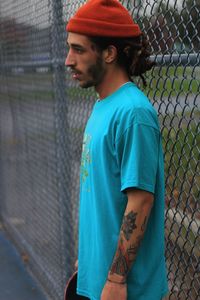 Side view man standing by chainlink fence