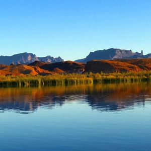 Scenic view of lake and mountains against clear blue sky