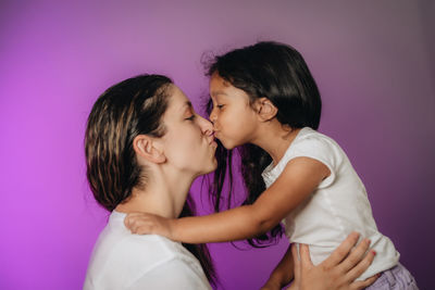 Mother and daughter against pink wall