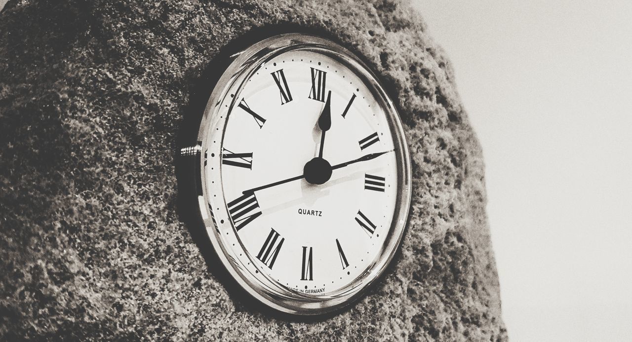 LOW ANGLE VIEW OF CLOCK ON WALL AGAINST WHITE BACKGROUND