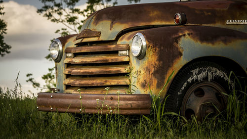 Close-up of abandoned car on field 