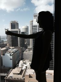 Side view of woman with champagne flute against buildings in city