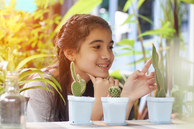  smiling girl touching cactus plant on table