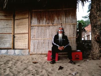 Full length of man sitting on seat against building