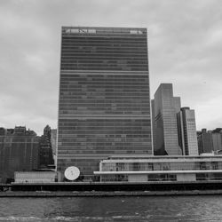 Modern buildings by river against sky in city