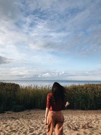 Side view of woman walking on field against sky