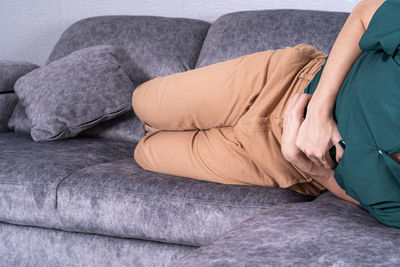 Midsection of woman relaxing on sofa at home