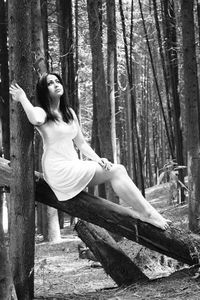 Young woman siting on log in forest