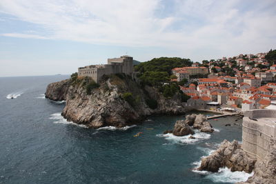 Buildings by sea against sky