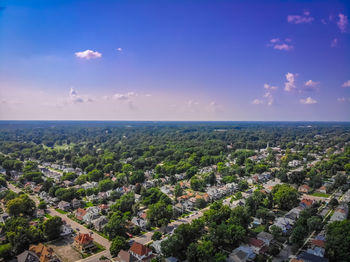 Aerial view of city by sea against blue sky