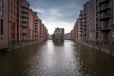 Canal amidst buildings in city against sky