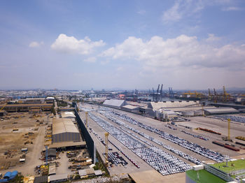 Aerial logistics commercial vehicles waiting to be load on to a car carrier ship at dockyard