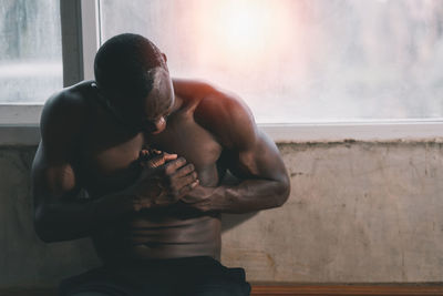 Rear view of shirtless man standing against wall