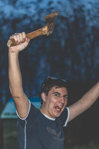 Portrait of cheerful man holding axe while standing outdoors