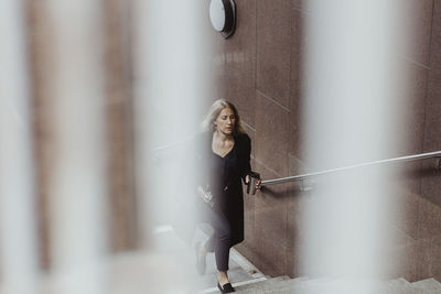 Businesswoman with coffee cup climbing staircase in city