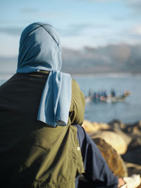 Rear view of woman wearing green shirt looking at fishing boat