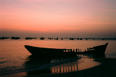 Silhouette boats moored on sea against sky during sunset