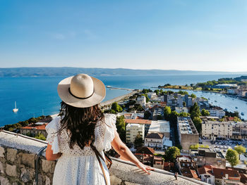 Rear view of woman standing on viewpoint above seaside town of omiš in croatia during summer holiday