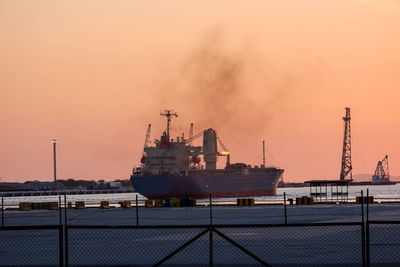 Ship at harbor against sky during sunset