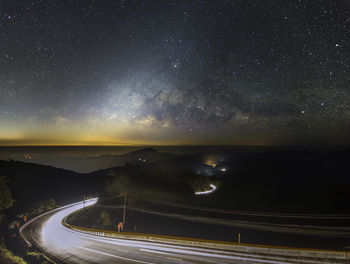 Light trails on road against sky at night