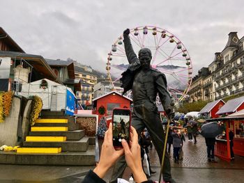 People photographing ferris wheel against sky