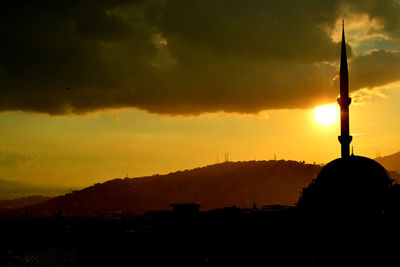 Silhouette mosque against cloudy sky during sunset